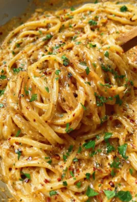 A plate of creamy caramelized onion pasta topped with fresh herbs.