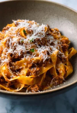 Creamy Fettuccine Bolognese topped with fresh herbs and Parmesan cheese