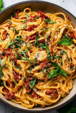 Creamy vegan sun-dried tomato pasta served in a bowl with fresh herbs