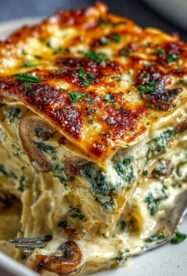 Creamy spinach mushroom lasagna topped with cheese in a baking dish