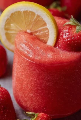 Refreshing frozen strawberry lemonade in a chilled glass with strawberries.