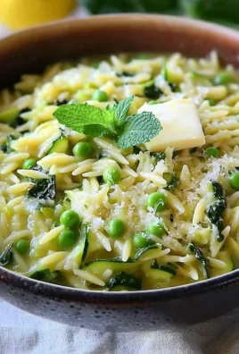Plate of lemon orzo with zucchini garnished with herbs