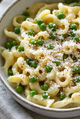 A delicious bowl of pasta and peas garnished with fresh herbs and cheese.