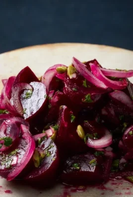 A colorful bowl of pickled beet salad garnished with fresh herbs.