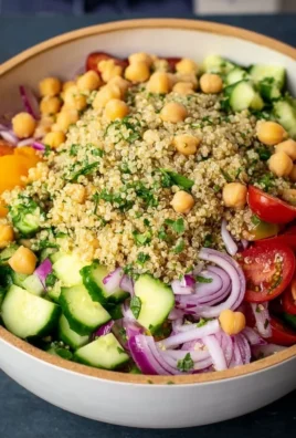 A vibrant quinoa chickpea salad with vegetables and dressing.