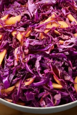 Colorful red cabbage slaw in a bowl with fresh vegetables and dressing