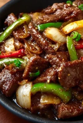 Delicious sizzling Chinese pepper steak with onions served on a plate.