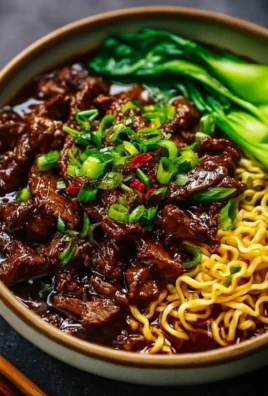 Plate of sticky beef noodles garnished with fresh herbs and vegetables