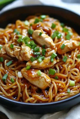 Plate of Sticky Garlic Chicken Noodles garnished with herbs and spices