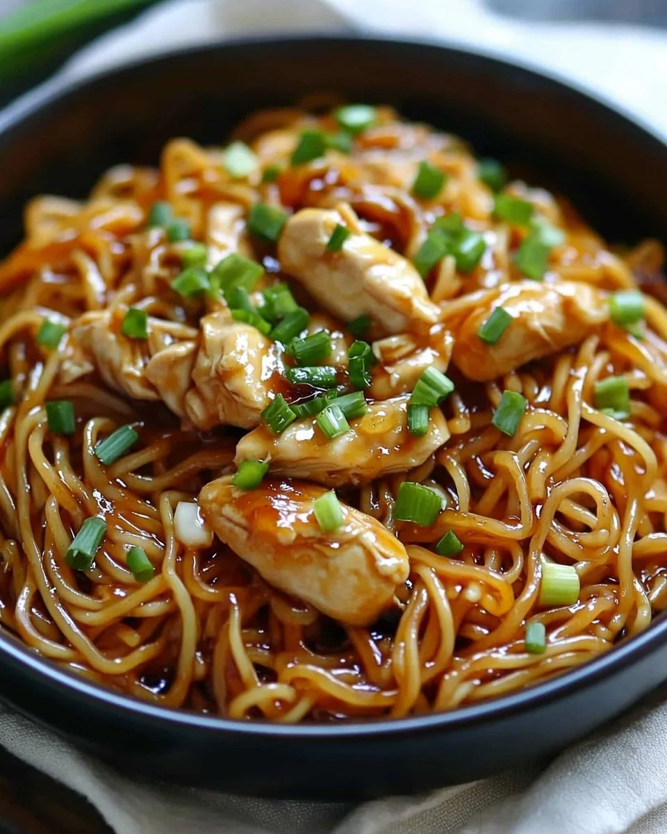 Plate of Sticky Garlic Chicken Noodles garnished with herbs and spices