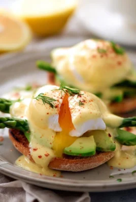 Delicious Avocado Eggs Benedict topped with hollandaise sauce and garnished with herbs.
