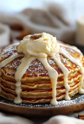 Stack of fluffy cinnamon roll pancakes topped with glaze and cinnamon swirl