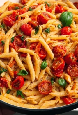 Creamy cherry tomato pasta garnished with fresh basil and cheese
