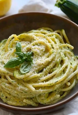 Creamy vegan zucchini pasta dish garnished with lemon and fresh basil