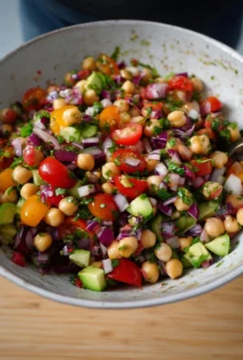 Vibrant rainbow chickpea salad with assorted fresh vegetables and herbs.
