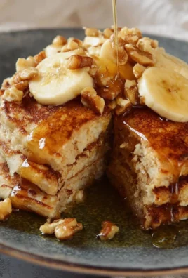Stack of easy banana nut pancakes topped with walnuts and syrup