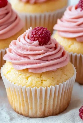 Lemon cupcakes topped with raspberry buttercream frosting on a plate