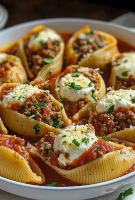 Baked stuffed pasta shells filled with cheese and herbs, garnished with marinara sauce.