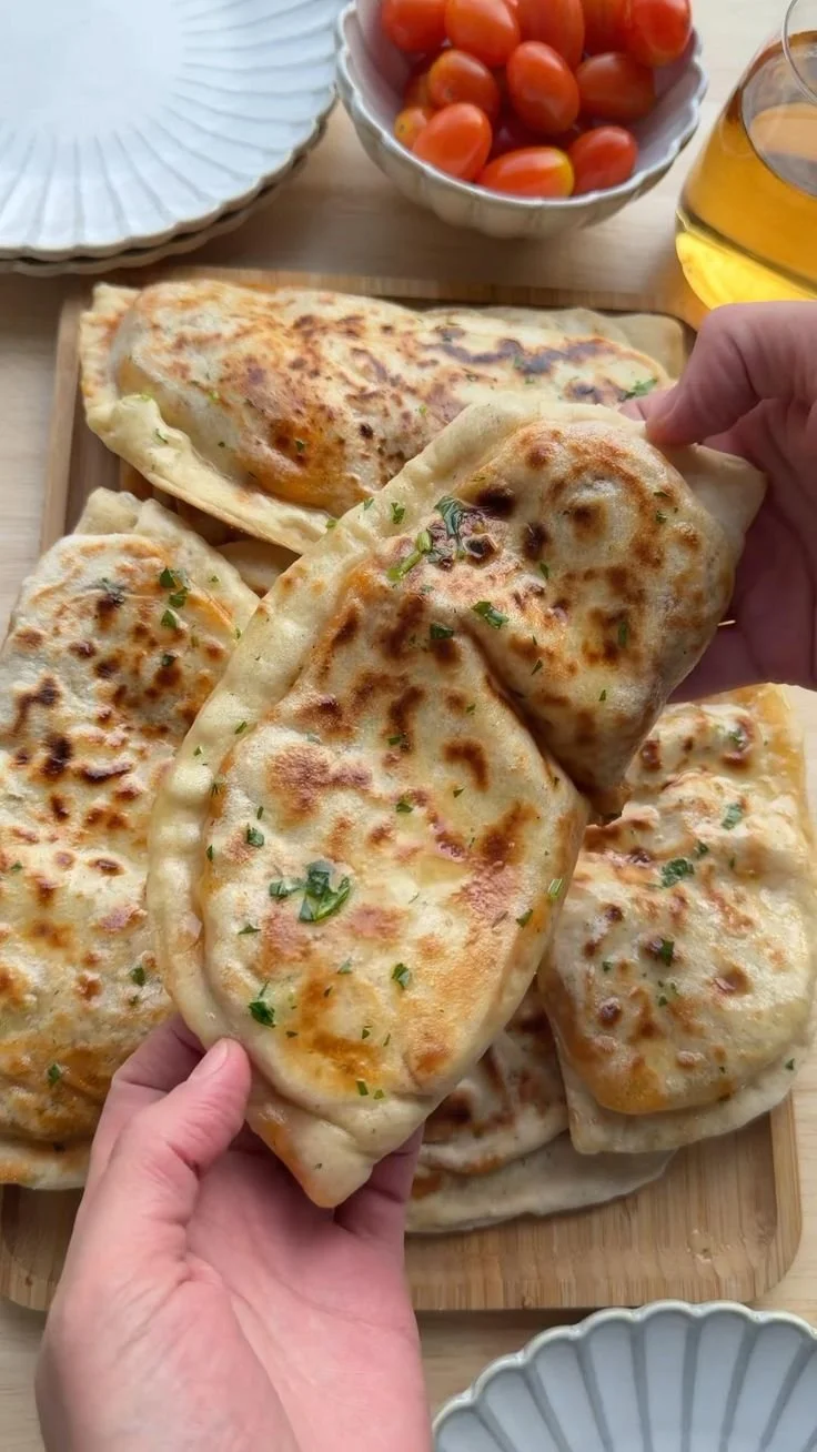 Flatbread topped with rich butter chicken and garnished with fresh herbs