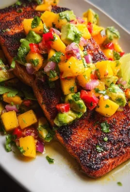 Grilled salmon topped with vibrant mango salsa on a white plate