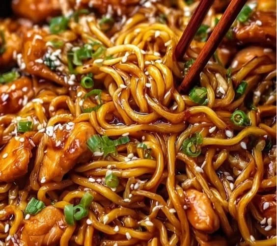 Plate of sticky garlic chicken noodles with vegetables and herbs
