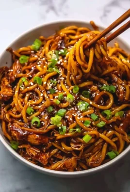 Sticky Garlic Chicken Noodles served in a bowl garnished with herbs.