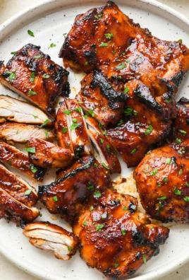 Oven-baked caramelized BBQ chicken thighs on a serving plate