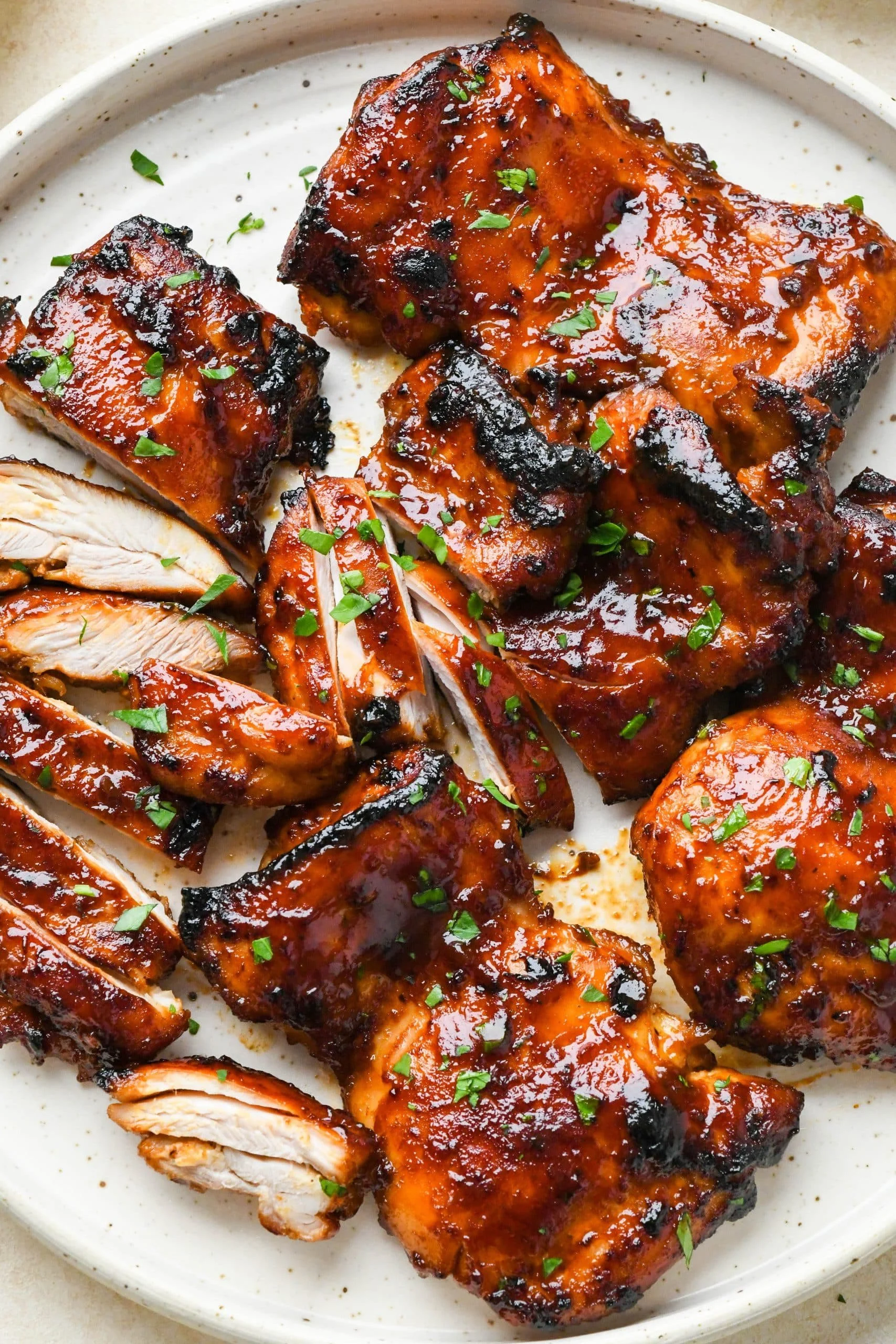 Oven-baked caramelized BBQ chicken thighs on a serving plate