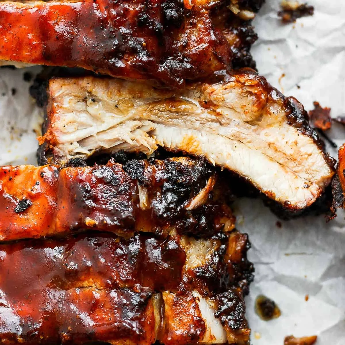 Delicious grilled ribs served with barbecue sauce on a wooden platter