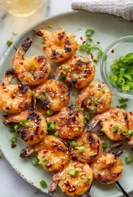 Juicy grilled Bang Bang Shrimp skewers served with zesty sauce.