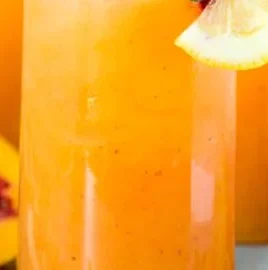 Homemade Peach Lemonade in a glass with fresh peaches and lemons