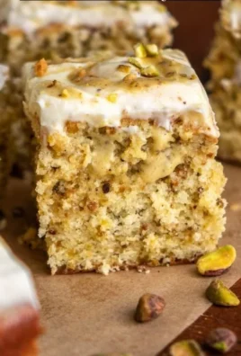 Slice of moist pistachio cake topped with creamy frosting and crushed pistachios