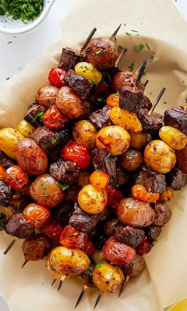 Rosemary garlic steak kebabs grilling on skewers with herbs