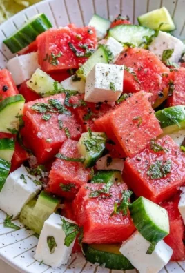 Fresh watermelon cucumber feta salad in a bowl, garnished with herbs
