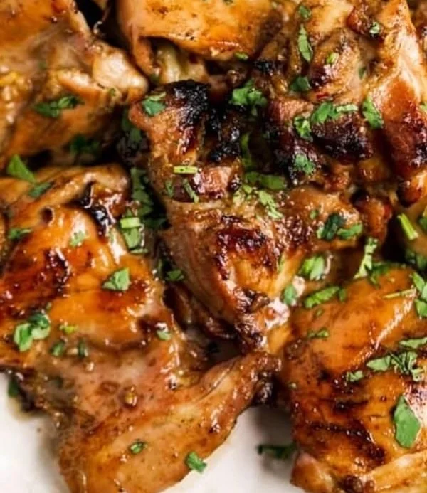 Grilled Thai chicken marinated with herbs and spices, served on a plate.