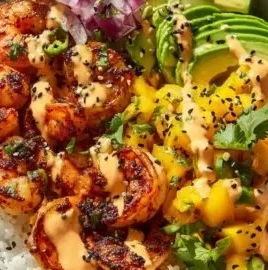 A colorful charred shrimp and avocado bowl garnished with fresh vegetables and herbs.