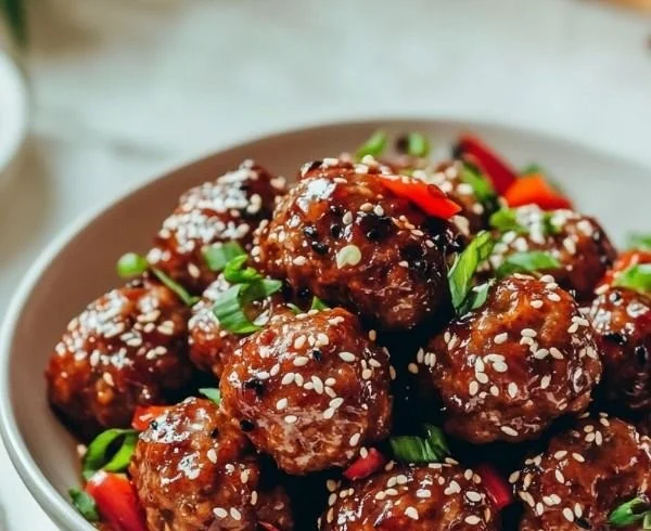 Asian meatballs served with dipping sauce and garnished with green onions.