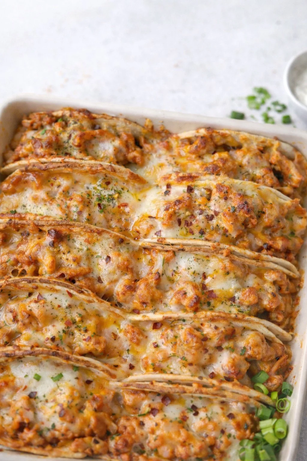 Baked chicken bacon ranch tacos topped with cheese and fresh herbs