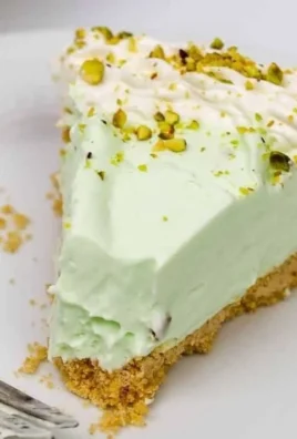 Slice of cool and creamy pistachio pie topped with whipped cream and pistachios.