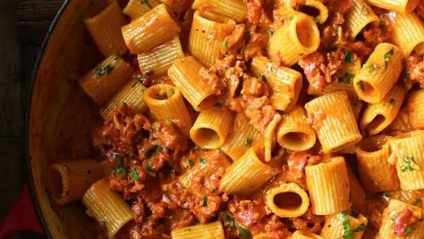 Creamy chorizo pasta dish served in a bowl, garnished with herbs.