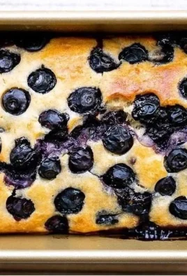 Slice of easy lemon blueberry bread with fresh berries on a plate.