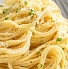 Plate of garlic buttered noodles garnished with parsley and parmesan cheese