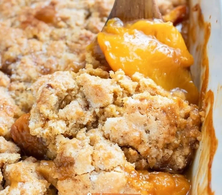 Gluten-free peach cobbler fresh out of the oven, topped with a scoop of vanilla ice cream.