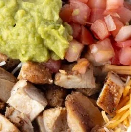 Grilled chicken burrito bowl with rice and beans, topped with fresh ingredients