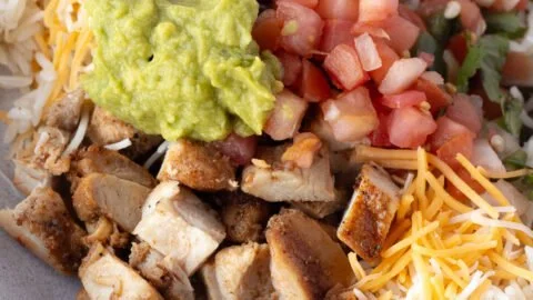 Grilled chicken burrito bowl with rice and beans, topped with fresh ingredients