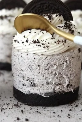 No-Bake Oreo Cheesecakes topped with crushed Oreos and chocolate drizzle