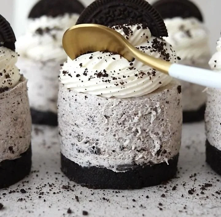 No-Bake Oreo Cheesecakes topped with crushed Oreos and chocolate drizzle