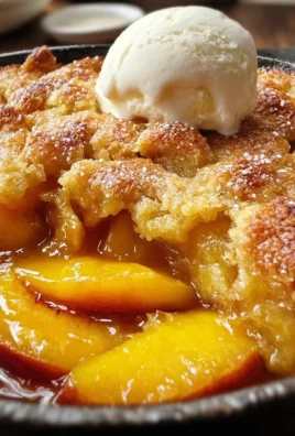 Deliciously baked peach cobbler served warm with a scoop of ice cream.