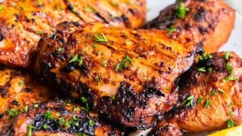 Smoky grilled paprika chicken served on a plate with fresh herbs